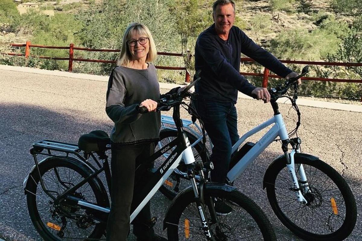 um homem e uma mulher parados ao lado de uma bicicleta