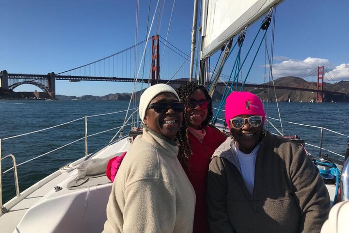 Tres personas en un barco con el puente Golden Gate al fondo