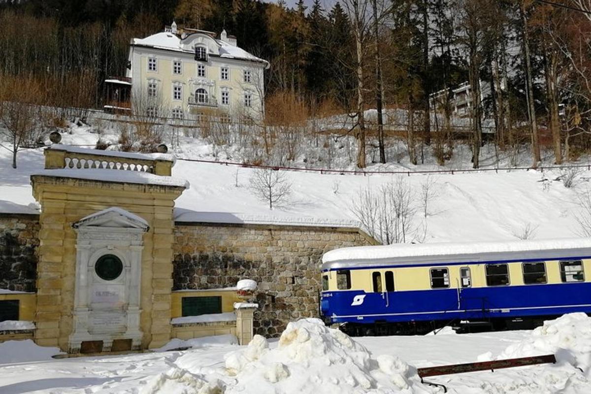 Modrý a žlutý vlak zaparkovaný vedle budovy ve sněhu