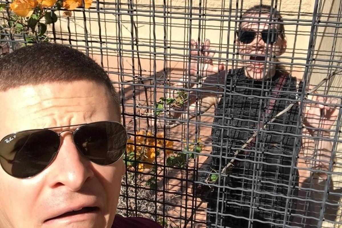 a man wearing sunglasses standing next to a cage
