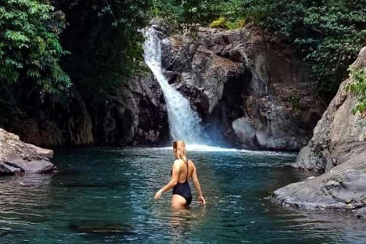 a woman in the water in front of a waterfall