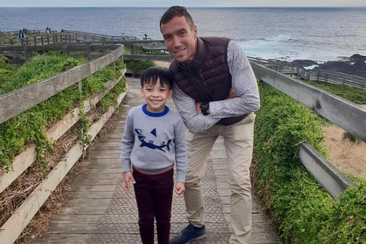 Un hombre y un niño caminando por un sendero cerca del océano.