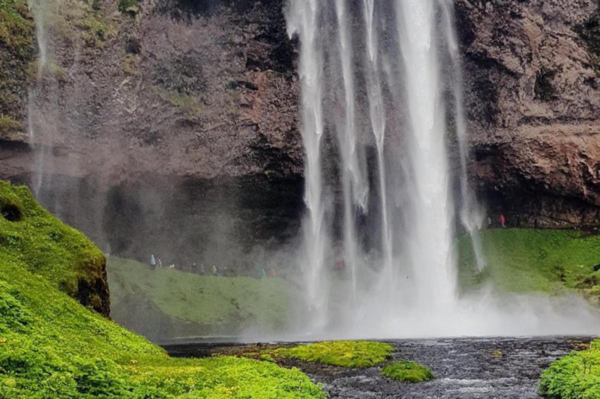 una cascada al mig d'una muntanya amb gent dempeus a sota
