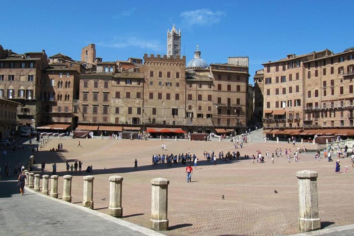 Un grupo de personas caminando por una gran plaza con edificios.