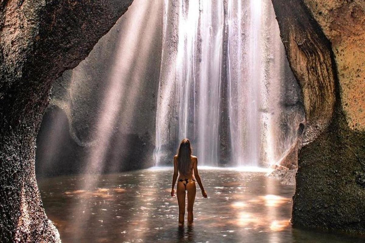 eine Frau, die vor einem Wasserfall im Wasser läuft