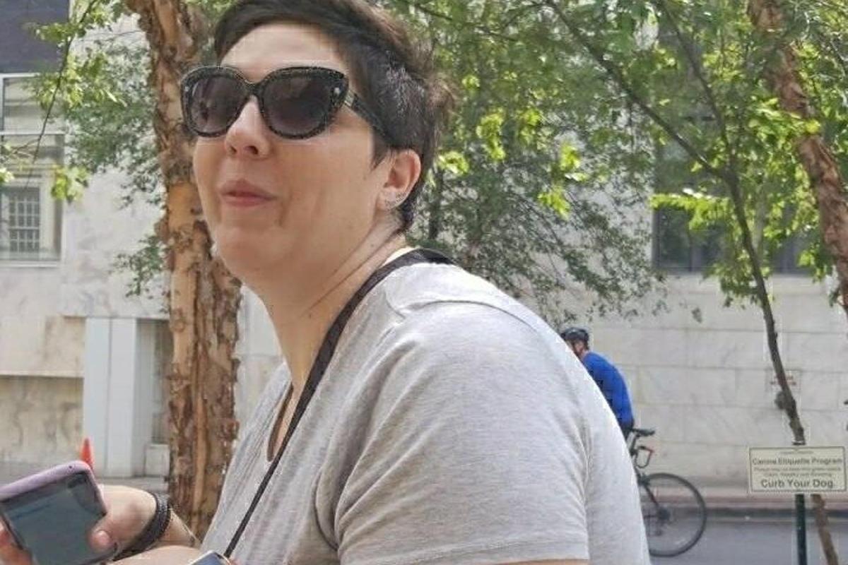Egy napszemüveget viselő nő a mobiltelefonját nézi