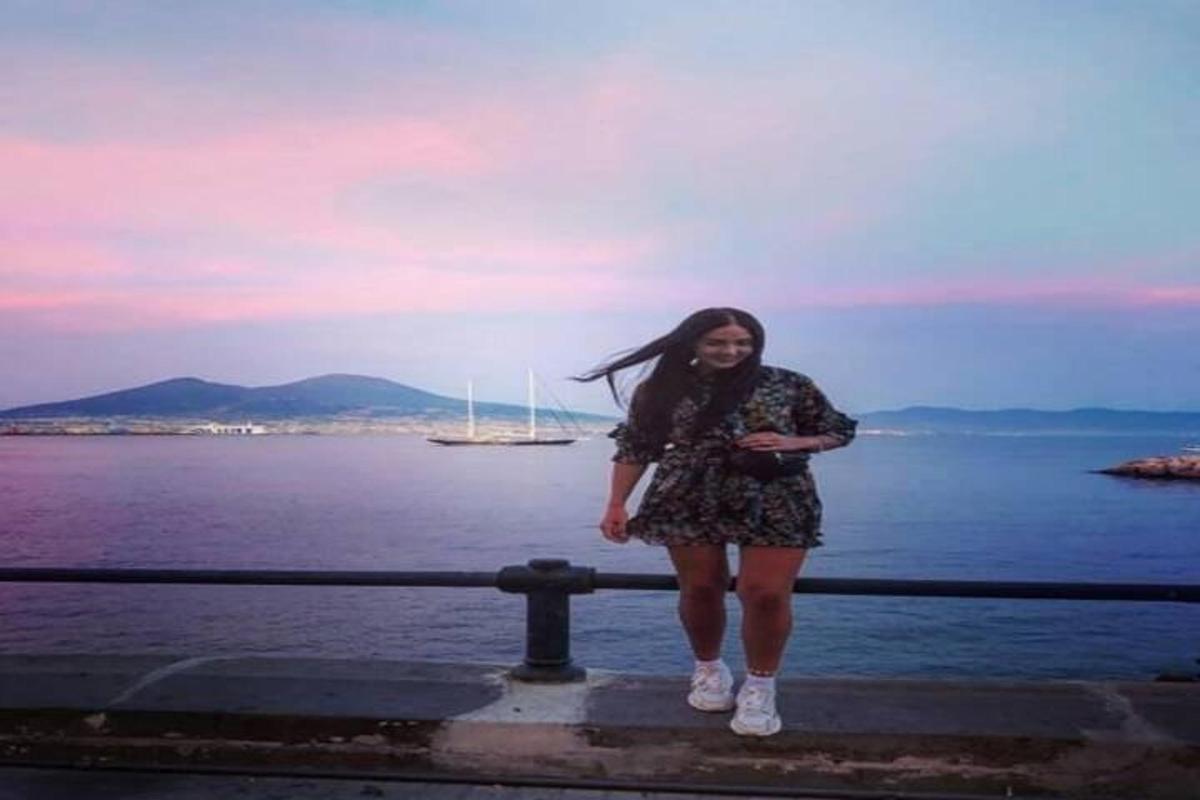 uma mulher em pé em um corrimão perto da água