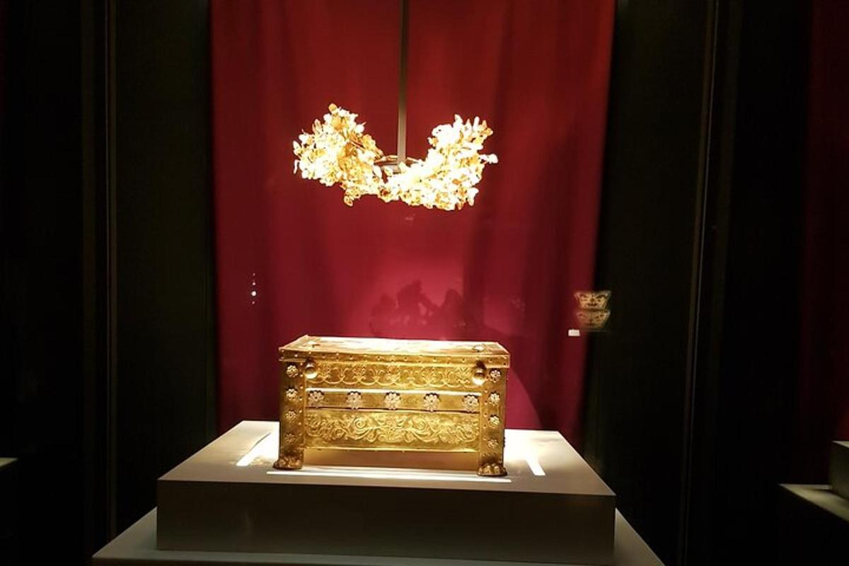 een gouden doos tentoongesteld voor een rood gordijn