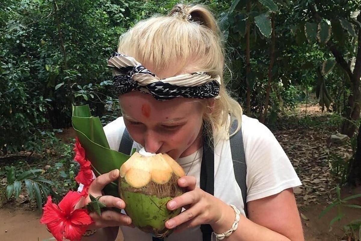 een vrouw eet een kokosnoot in een bos