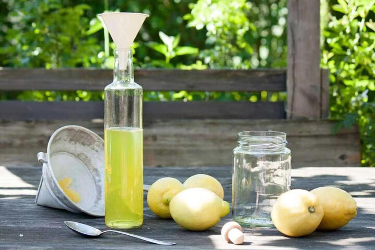 una ampolla de líquid verd i algunes pomes sobre una taula