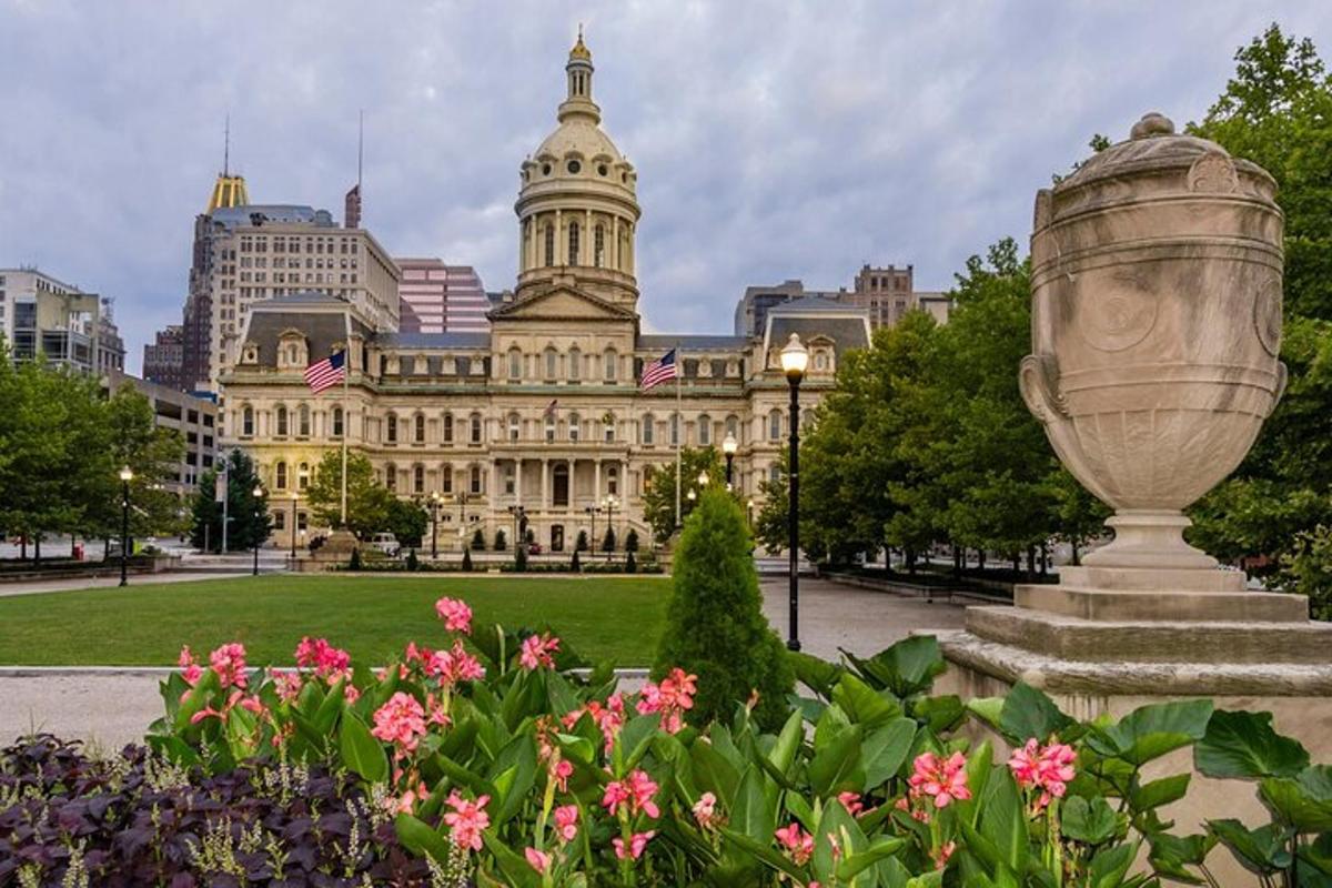 a large building with a statue in a park with flowers