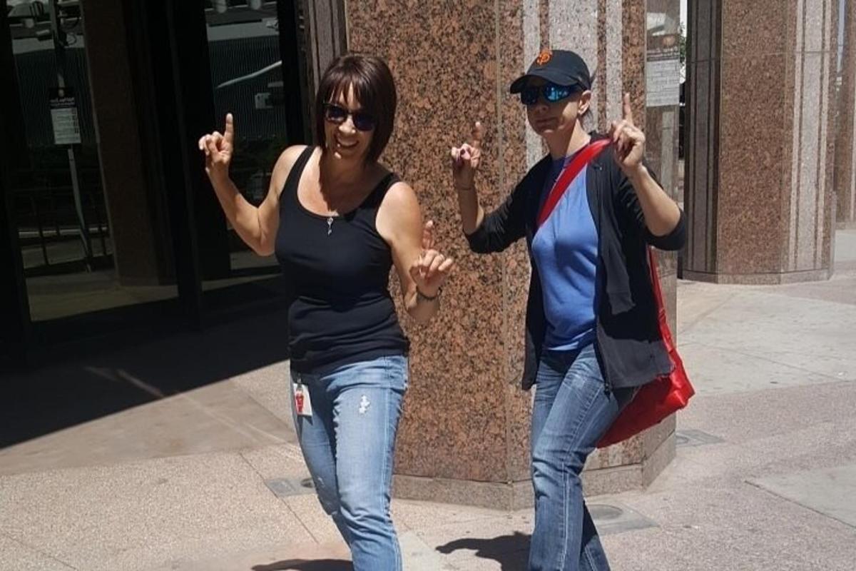 due donne camminano per strada con le mani alzate