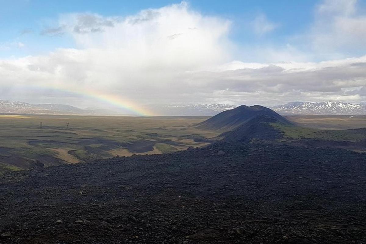 regnbogi í miðjum akri með fjalli