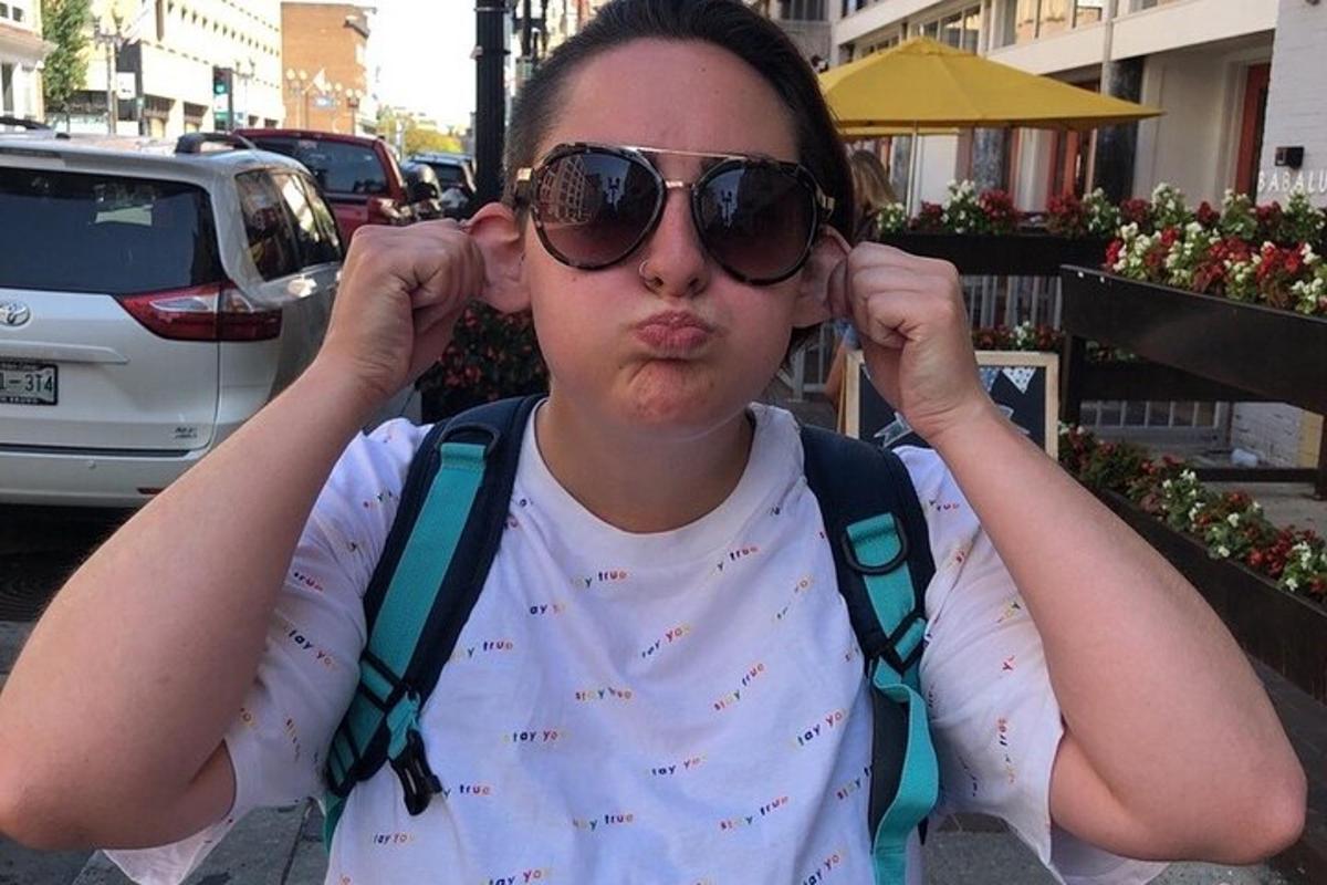 a woman wearing sunglasses and suspenders is sitting
