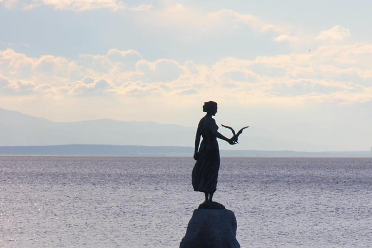 una estàtua d'una dona dempeus sobre una roca a l'oceà