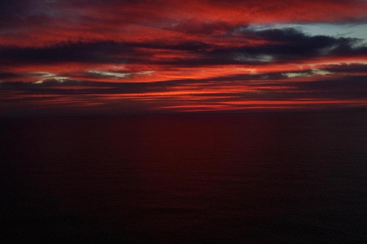 um pôr do sol sobre o oceano com um céu vermelho