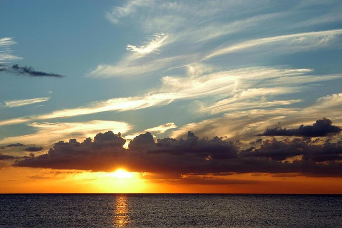 auringonlasku meren yllä pilvien ympäröimänä