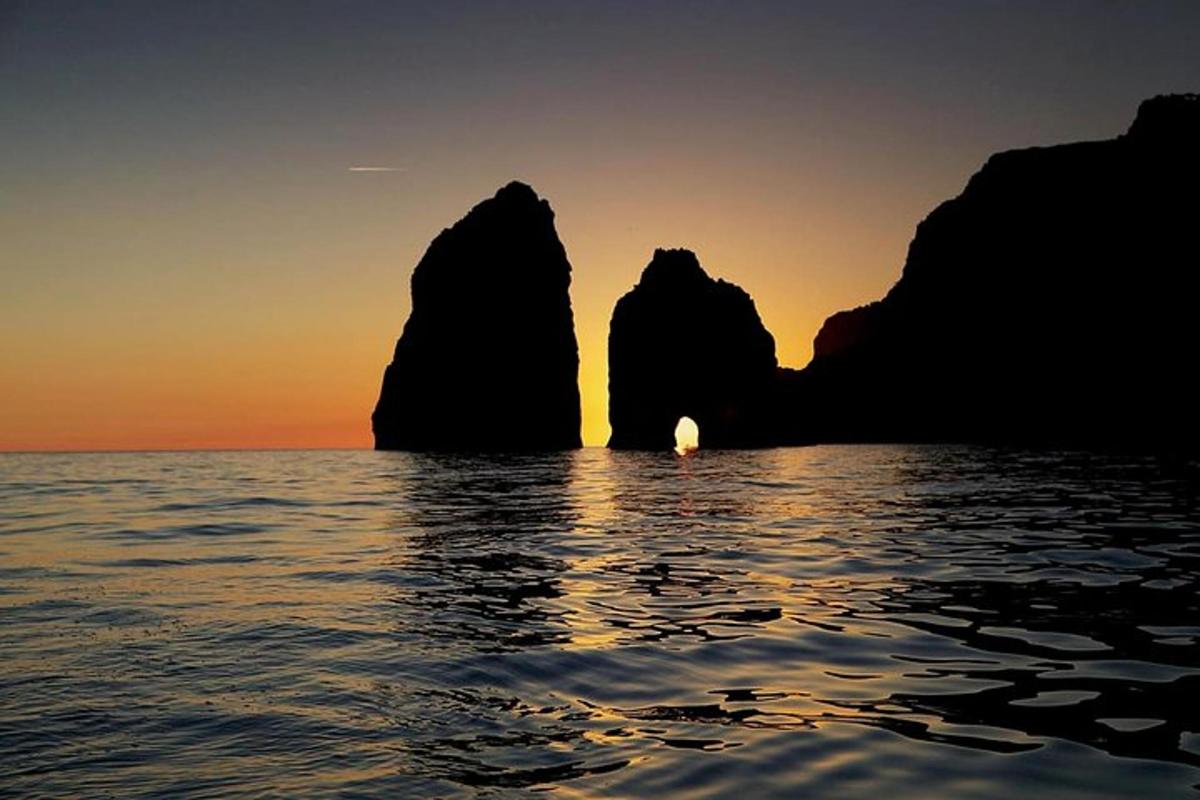 Západ slunce nad oceánem s kameny ve vodě