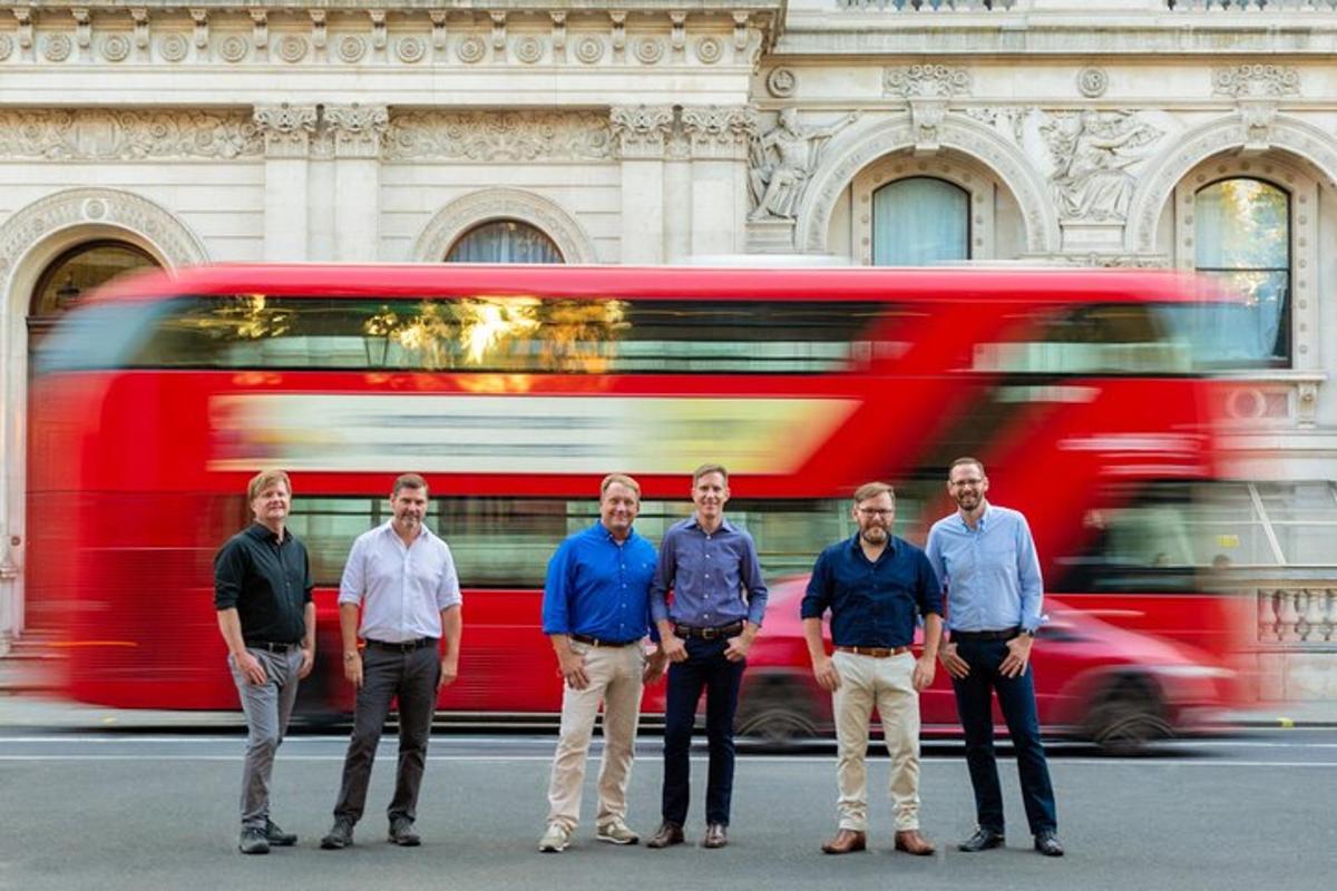 um grupo de homens parados em frente a um ônibus vermelho