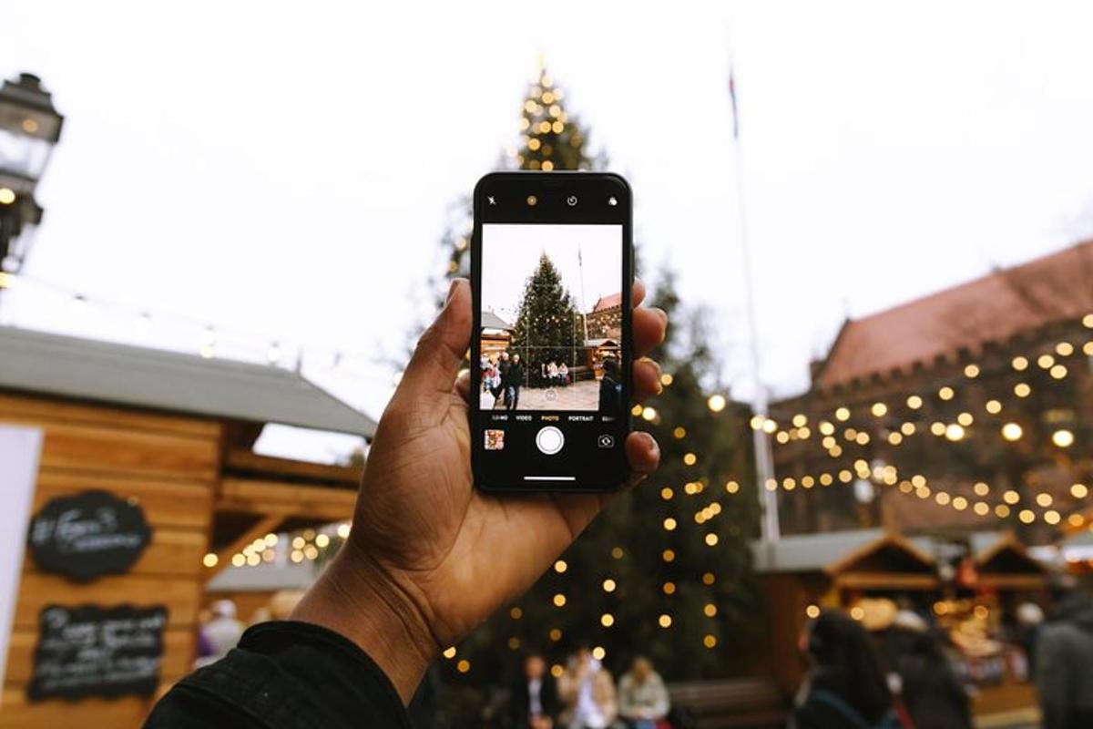a person holding up a cell phone in front of a christmas tree