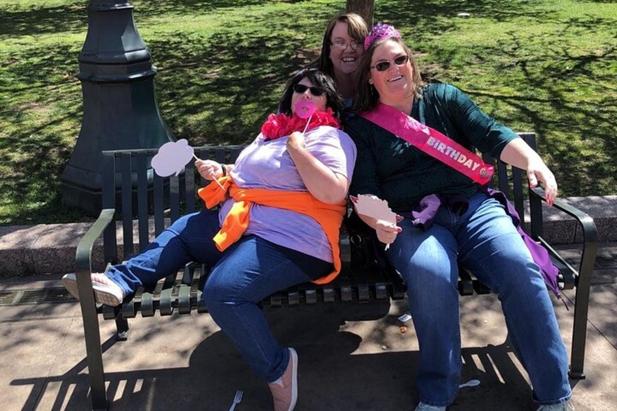 three women sitting on a bench in a park