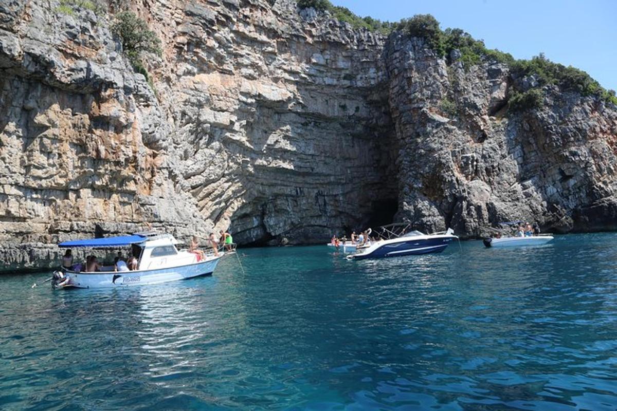 um grupo de barcos na água perto de um penhasco