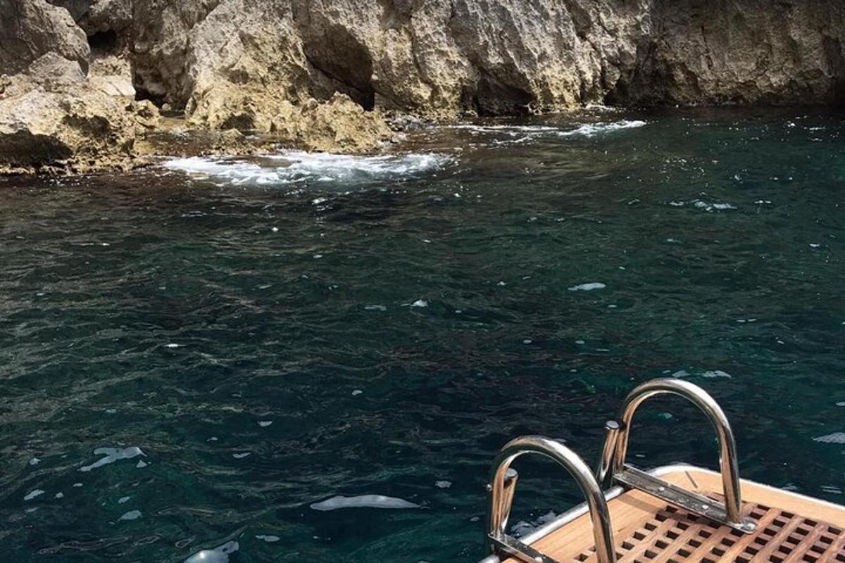 μια βάρκα στο νερό δίπλα σε έναν απότομο βράχο