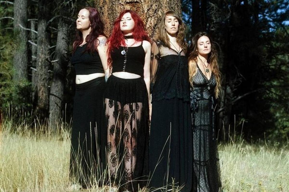 un gruppo di quattro donne in piedi accanto a un albero