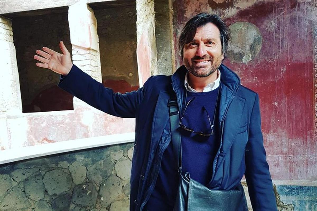 un bărbat într-o jachetă albastră stând lângă un perete