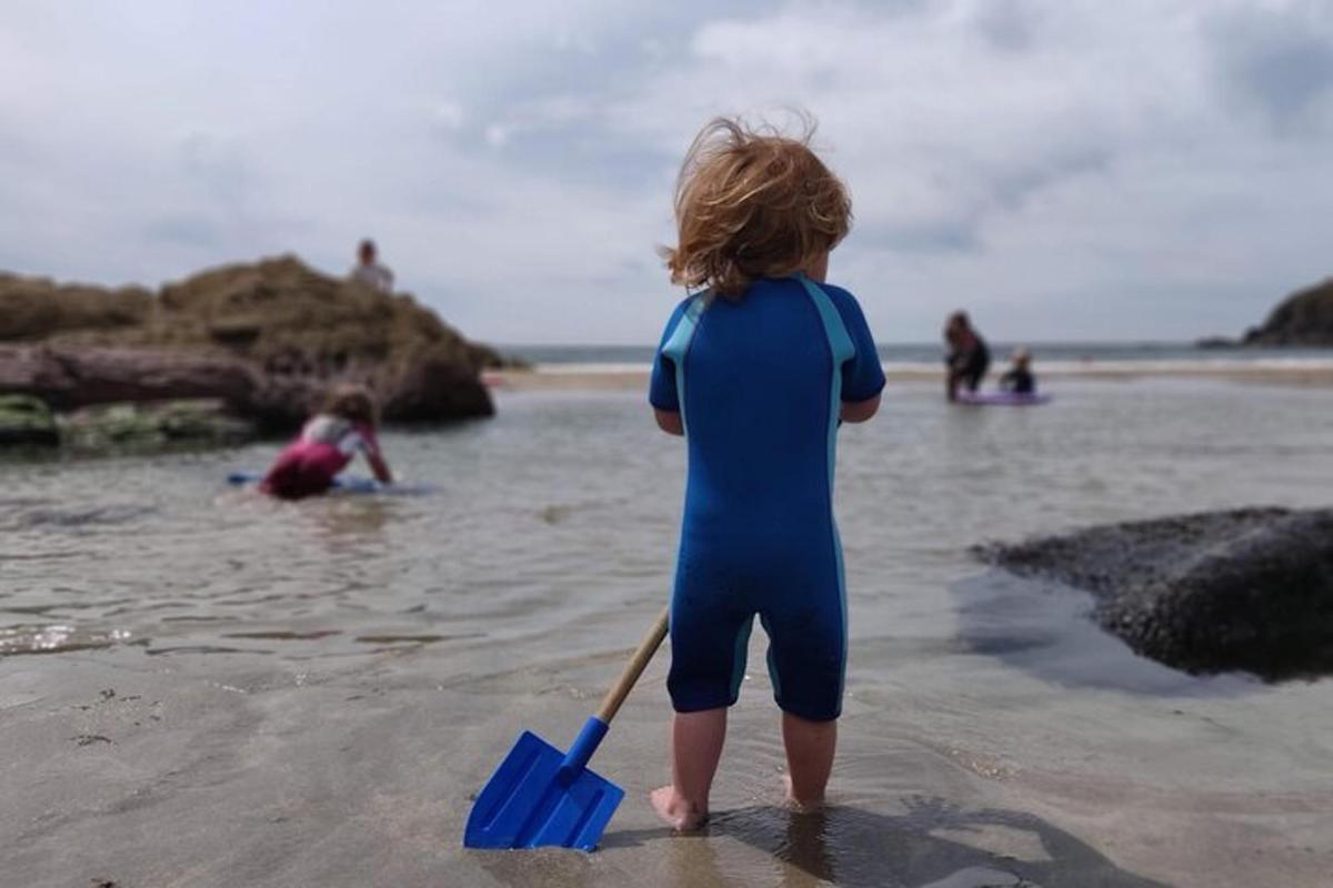 a young child standing on the beach with a paddle