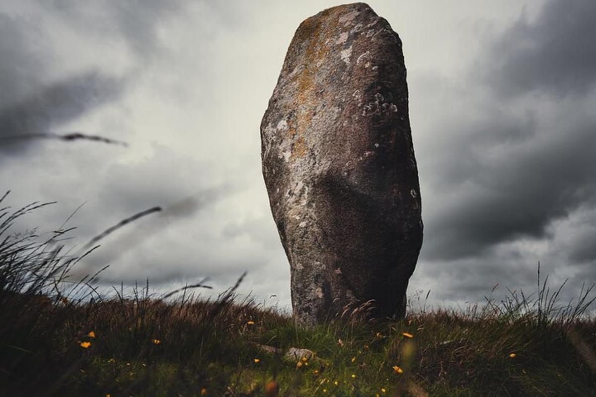 a large rockolith in a field with a cloudy sky