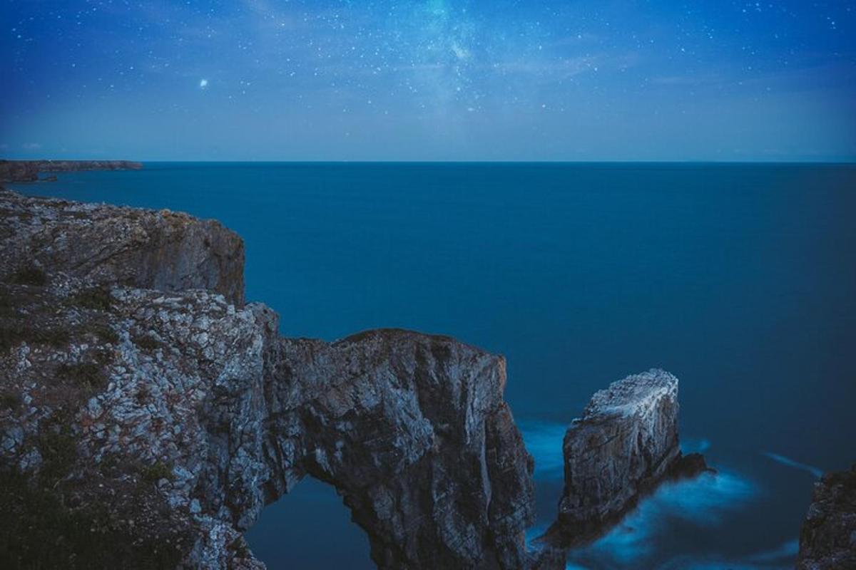 a night view of a rock formation in the water