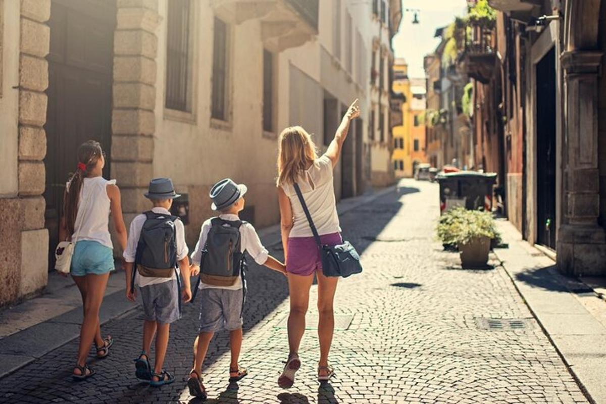 una dona i tres nens caminant per un carrer