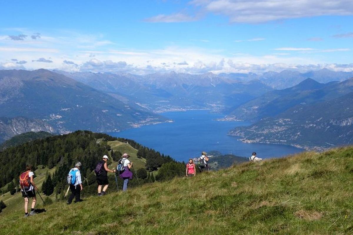 a group of people walking on a hill overlooking a lake