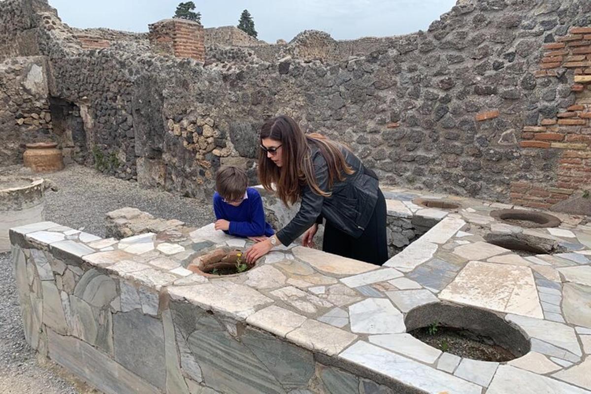 una dona i un nen drets al costat d'un mur de pedra