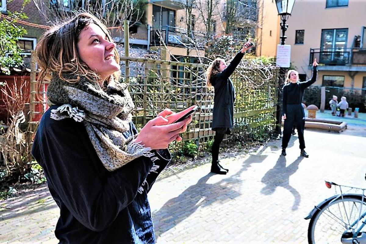 skupina žen stojících na chodníku a dívajících se do svého mobilního telefonu