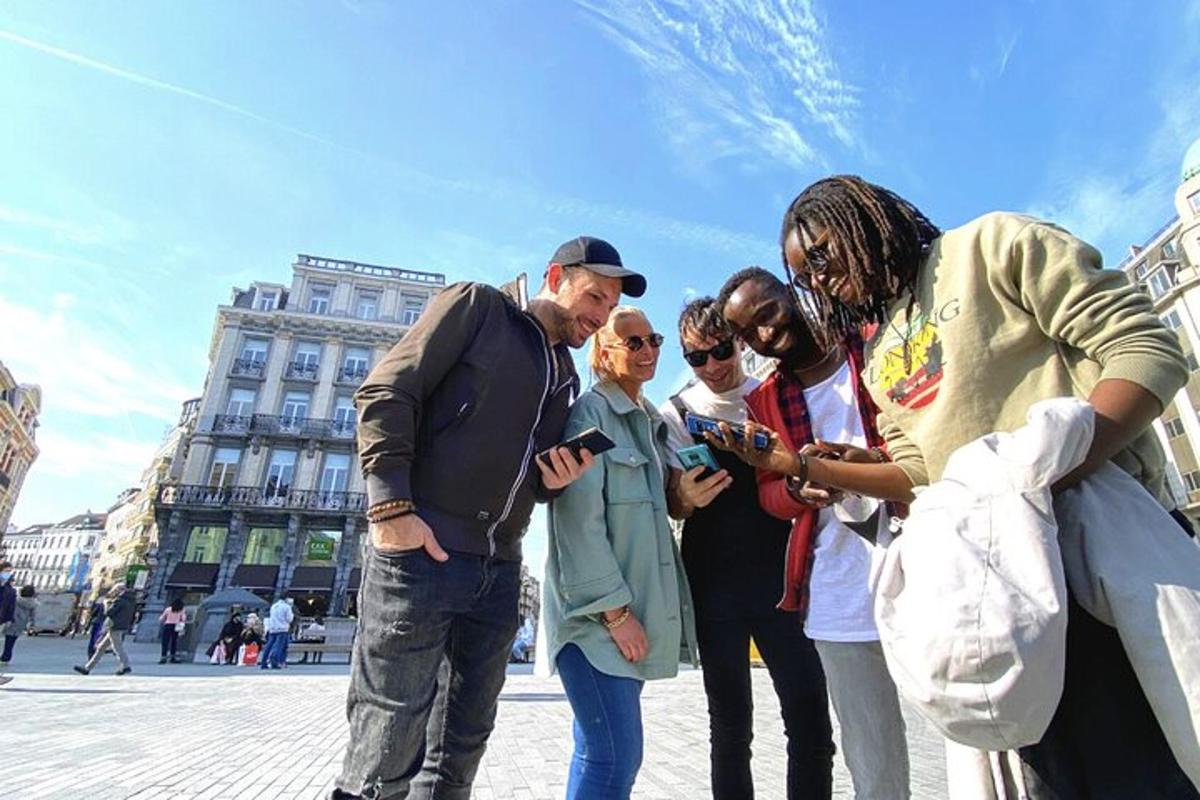 Un grupo de personas paradas mirando sus teléfonos celulares.
