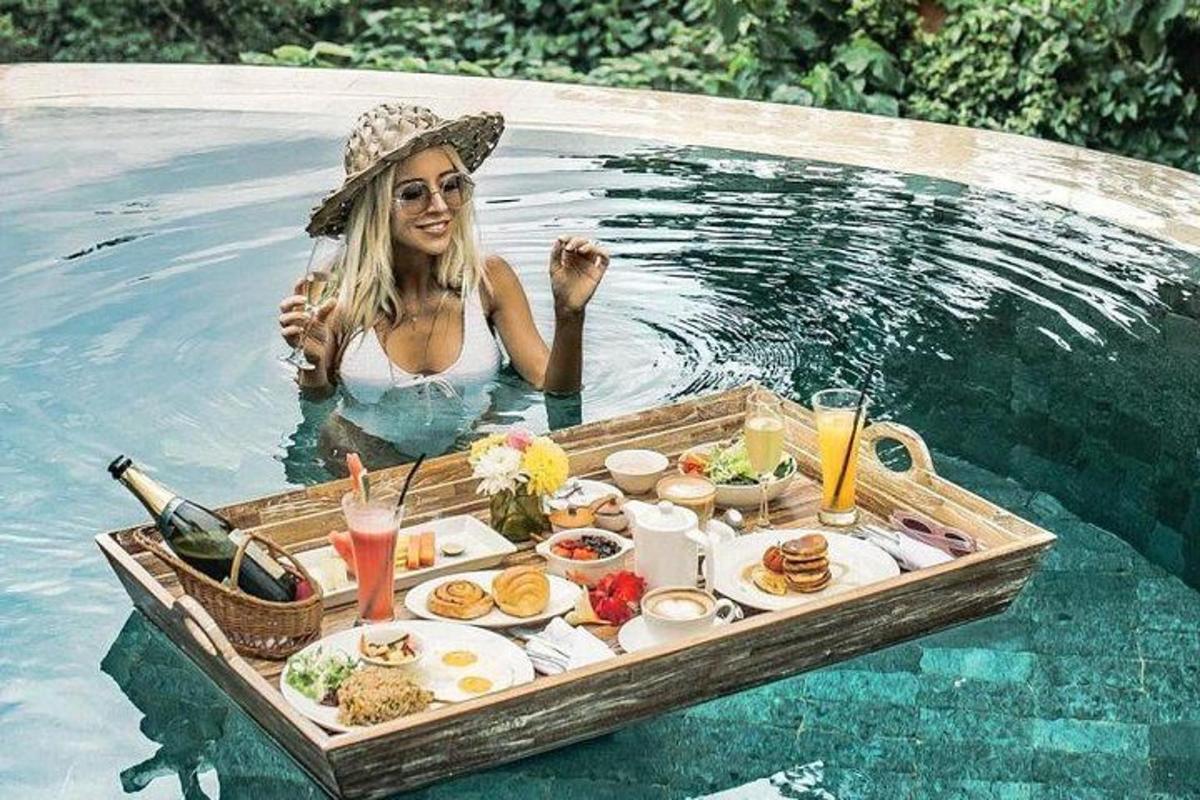 seorang wanita di dalam kolam dengan dulang makanan di dalam air