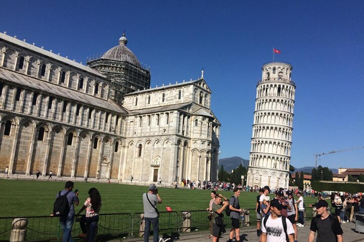 un gruppo di persone in piedi davanti a un edificio con la torre pendente