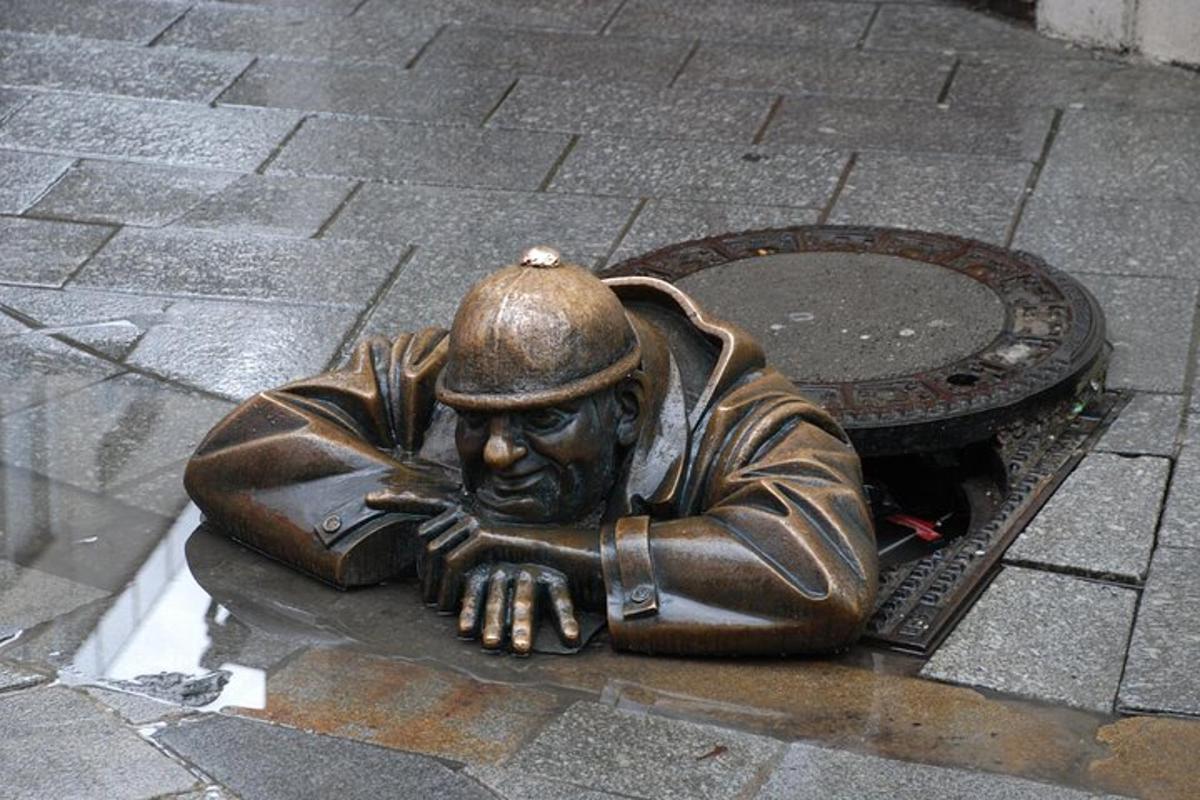 uma estátua de bronze de um homem deitado em um bueiro