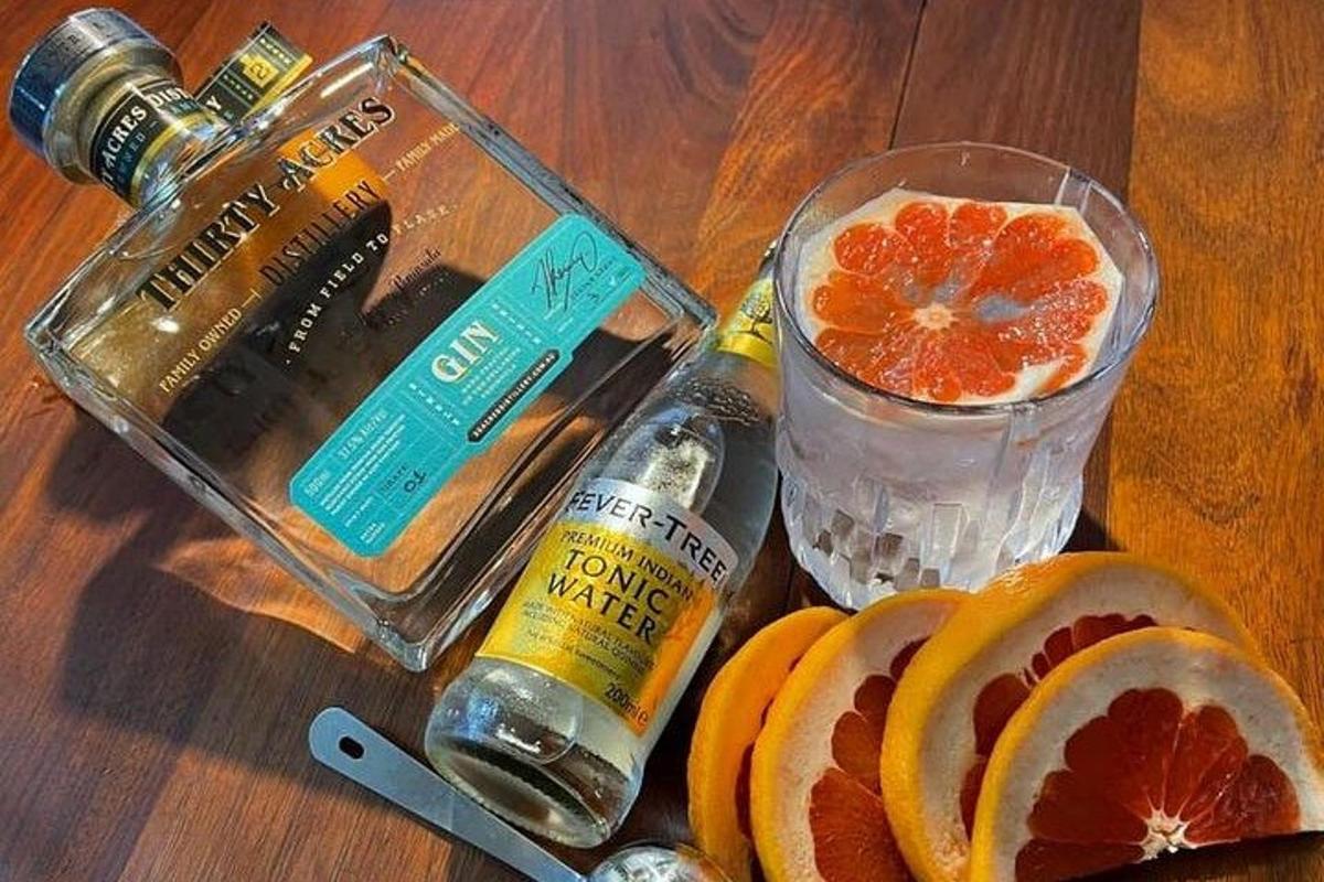 a table with a bottle of alcohol and a glass of orange juice