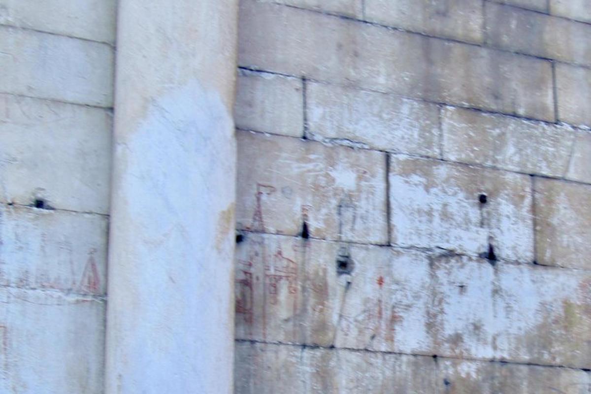 un muro di pietra con una colonna accanto a un edificio