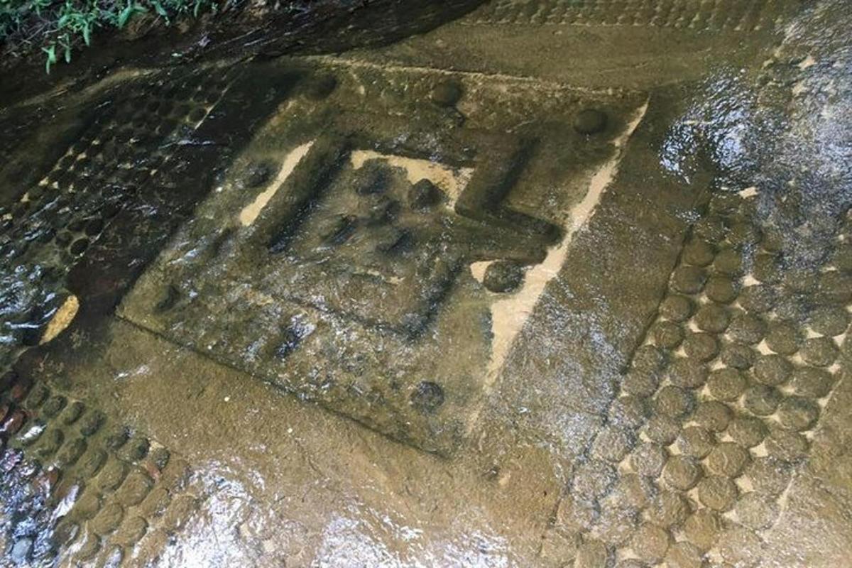 Una vieja rejilla de metal en el suelo con agua.