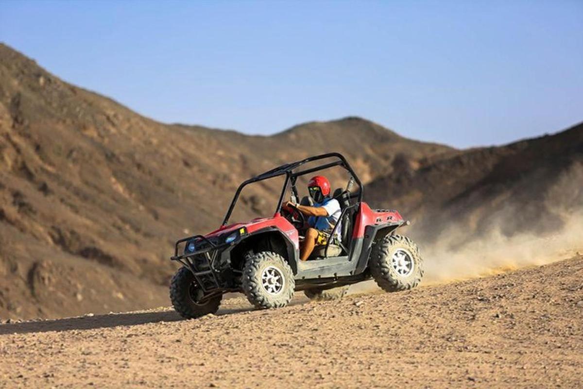 uma pessoa pilotando um quadriciclo vermelho no deserto