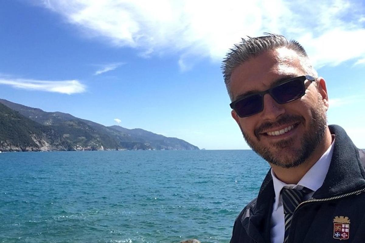 un uomo che indossa occhiali da sole e un abito in piedi vicino all'acqua
