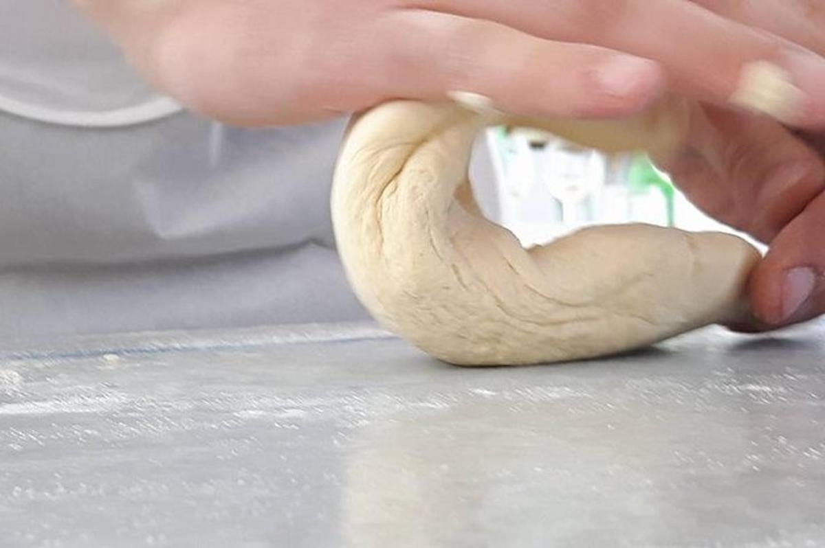 o persoană frământă o bucată de aluat