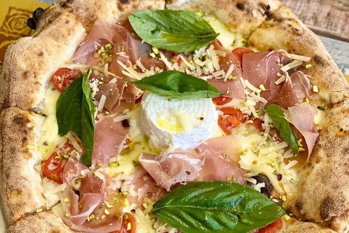 una pizza con prosciutto e foglie verdi sopra