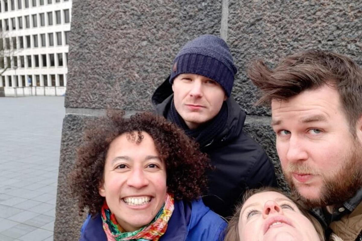 hópur þriggja manna sem stendur við vegg
