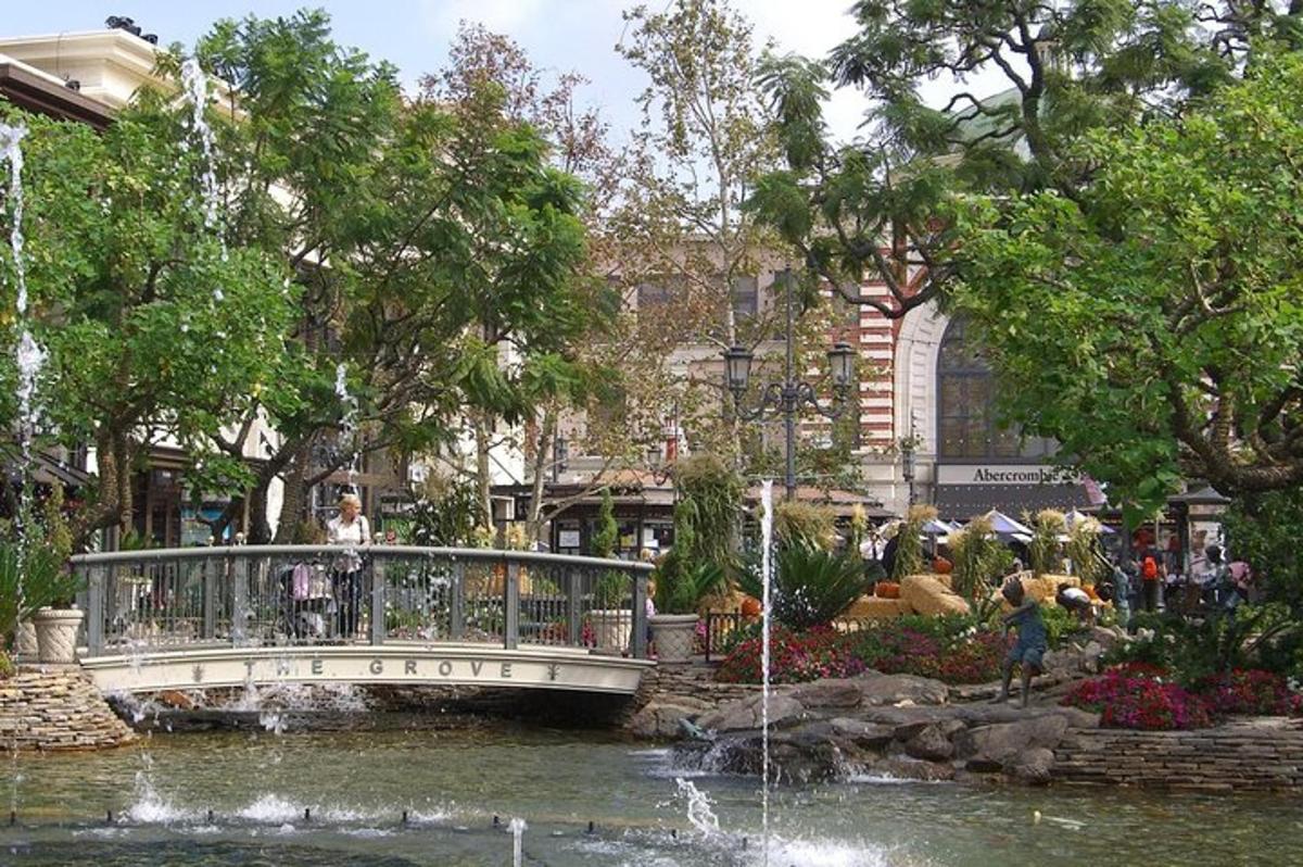 a bridge over a pond in a park with a fountain