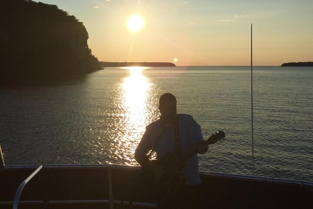 a man sitting on a boat playing a guitar